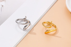 Detail van slangvormige ringen in goud en zilver met ingelegde kristallen ogen