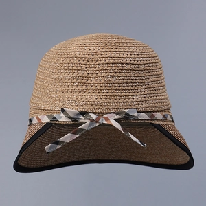 Detail of elegant straw sun hat with woven texture and a classic checkered ribbon bow