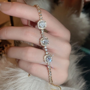 Gros plan d'un bracelet doré ajustable avec breloques en zircone et fermoir coulissant