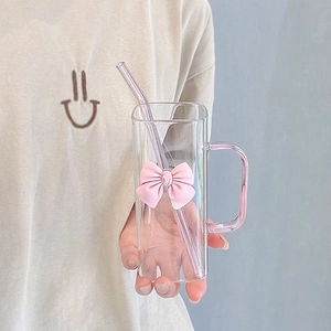 Detail of a square glass cup with pink handle, straw, and cute 3D bow decoration