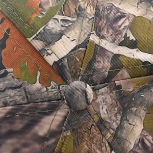 Macro shot of forest camouflage baseball cap top showing stitching and crown button