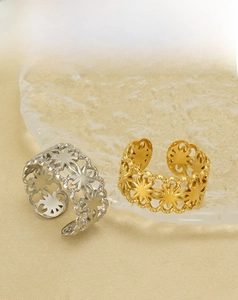 Close-up of gold and silver hollow star pattern rings on glass display base