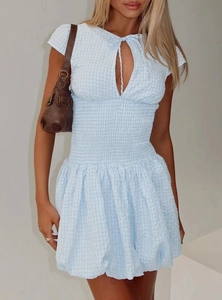 Detail of light blue plaid mini dress featuring smocked waist and cutout tie neckline