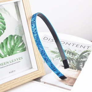 Sparkly blue glitter headband with non-slip teeth for girls, shown on a wooden frame