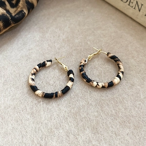 Close-up of leopard print hoop earrings with gold metal finish on beige felt background