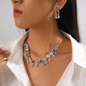 Detail of silver vintage floral necklace set with colorful gems and tassels on model