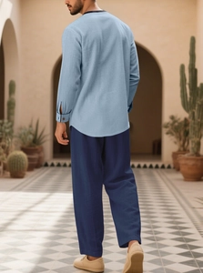 Close-up of a men's light blue linen shirt and dark blue pants in a desert outdoor setting