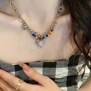 Gros plan d'un collier argenté avec perles colorées et pendentif en forme de cœur serti