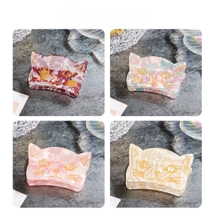 Detail view of four cute acrylic cat-shaped hair claws in various colorful floral patterns
