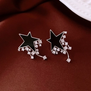 Macro detail of asymmetric black star earrings with silver trim and zircon tassels