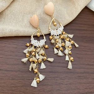 Detail of bohemian heart earrings with wooden beads and cream fringe tassels