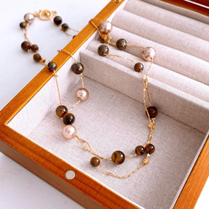Detailed view of Tiger Eye stone and champagne pearl beaded necklace in a wood jewelry box