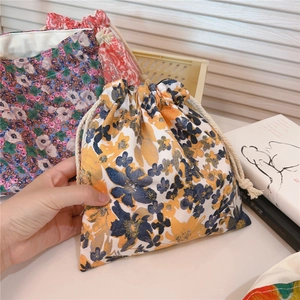Detailed view of floral pattern cotton drawstring storage pouch held by hand for scale