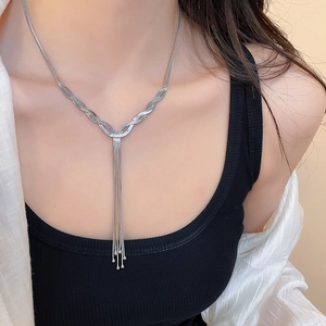 Close-up of a silver Y-shaped tassel necklace with layered wavy chains and metallic beads