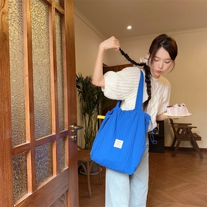 Detail shot of the striped drawstring tote bag in bright blue nylon with a brand patch