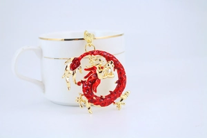 Detail view of a gold and red dragon keychain with enamel finish and white bead