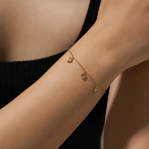 Elegant gold plated heart charm bracelet with sparkling white zircons on a woman's wrist