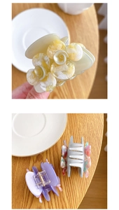 Detailed view of floral acetic acid hair claws in yellow, grey, and purple colors