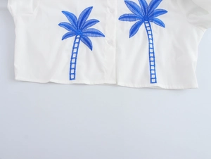 Detailed view of white cotton-linen cropped shirt with blue palm tree embroidery