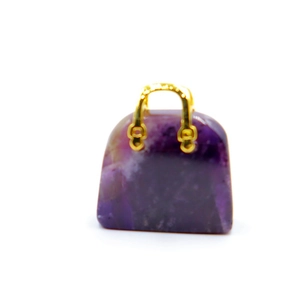 Detailed shot of amethyst crystal pendant shaped like a handbag with gold metal handle