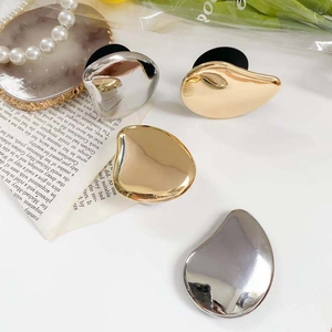 Detail showing irregular bean-shaped metal phone grips in gold and silver mirror finishes