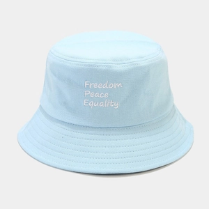 Détail de la broderie blanche 'Freedom Peace Equality' sur un chapeau bob en coton bleu clair