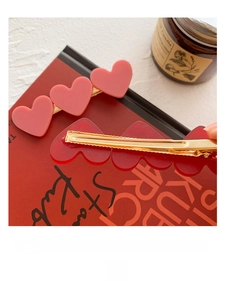 Close-up of pink and red heart-shaped acrylic hair clips on a red magazine