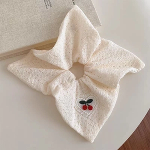 Detail of lace scrunchie featuring embroidered red cherries and pearl heart patch