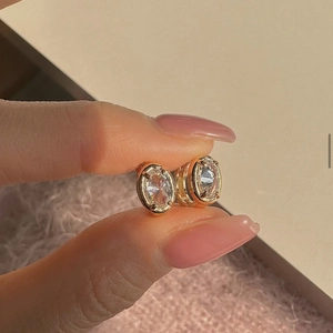 Close-up of a gold oval hoop earring featuring prong-set cubic zirconia stones
