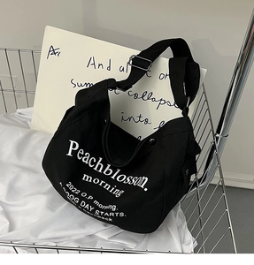 Détail d'un sac cabas en toile noire avec lettrage blanc dans un panier en métal argenté
