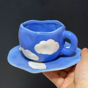 Macro detail of hand-pinched blue ceramic coffee cup with white cloud pattern