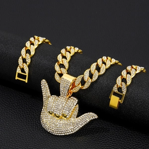 Close-up of hip hop gold Cuban link chain and iced out hand gesture pendant detail