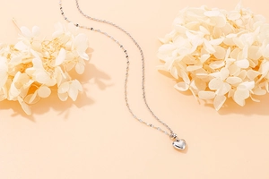 Macro view of silver heart pendant on a delicate chain over minimalist background