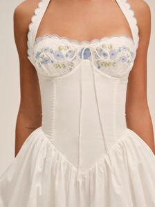 Detail of blue floral embroidery and tie-up drawstring on white halter mini dress