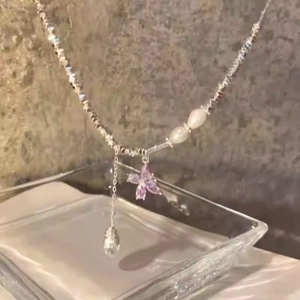 Primo piano che mostra le intricate perle d'argento e il ciondolo a farfalla in zircone viola.