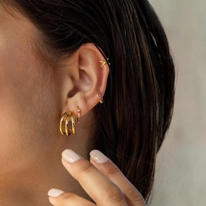 Close-up of gold ear cuff set featuring zircon hoops and minimalist X-shape clip on ear
