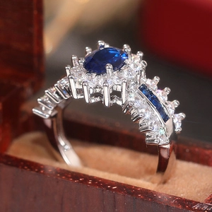 Makrofoto eines ovalen Saphir-Rings mit funkelndem Zirkonia auf einer hölzernen Schmuckschatulle