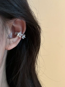 Close-up of minimalist silver star ear cuff with sparkling crystals worn on ear