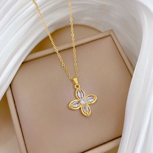 Detailed close-up of a gold clover necklace with sparkling crystals on a beige display