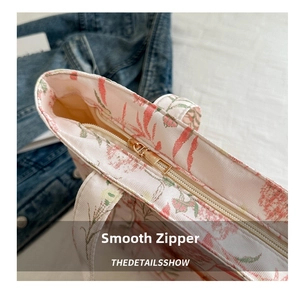 Detailed macro view of the smooth gold metal zipper on a floral canvas tote bag