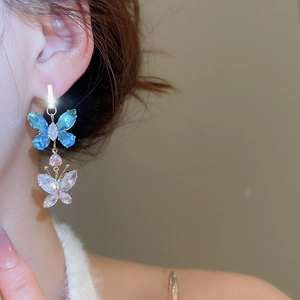 Close-up of elegant double butterfly drop earrings with blue and clear crystals on a model