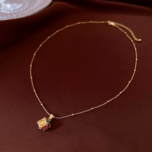 Close-up of 18K gold plated necklace with colorful opal stones on dark red silk