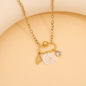 Detail view of gold shell and conch pendants on stainless steel necklace with zircon