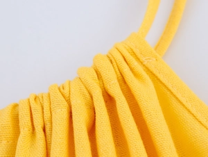 Detailed macro view of yellow linen-style fabric texture and drawstring pleated stitching