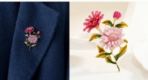 Detail of colorful enamel floral brooch with pink petals and green leaves on wool coat