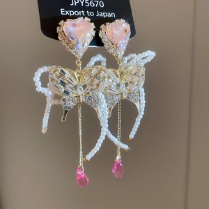 Macro detail of pink heart crystal butterfly earrings with pearl tassels and rhinestones