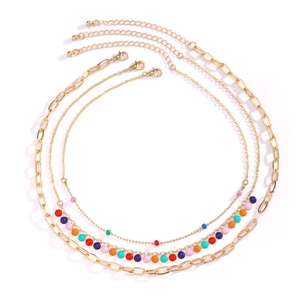 Detailed view of triple-layered gold necklaces with colorful beads and lobster clasps