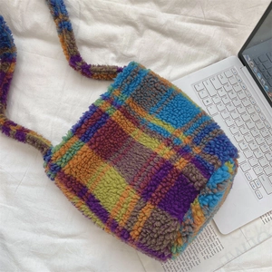 Detail of colorful plaid faux shearling bucket bag with soft plush texture and strap