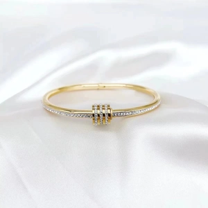 Macro shot of gold-plated bangle with micro-pave crystals on white silk background