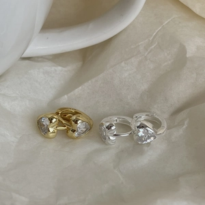 Detailed view of heart-cut zircon earrings with S925 silver stamp on textured background